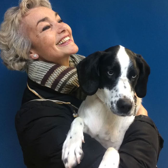 Señora con un perro mestizo negro y blanco en brazos en la clínica veterinaria El Jardín.