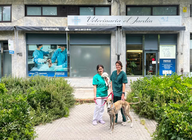 Maite y Liss con un galgo y un caniche delante de la clínica veterinaria El Jardín